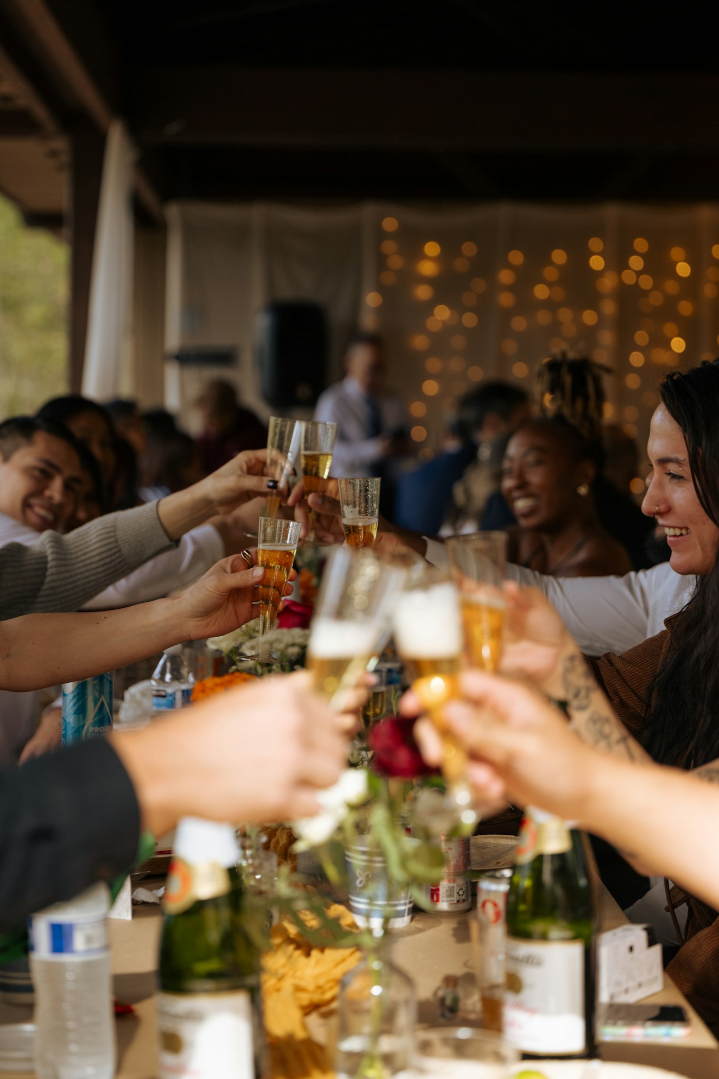 Guests toasting champagne under string lights at a reception