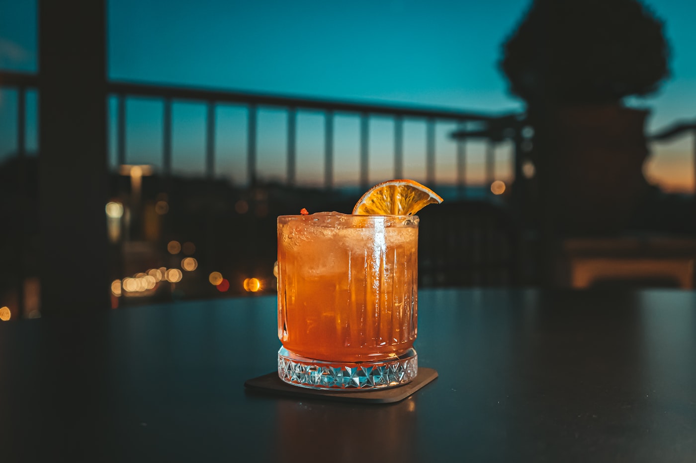 Cocktail with a citrus wheel at dusk, soft lights behind