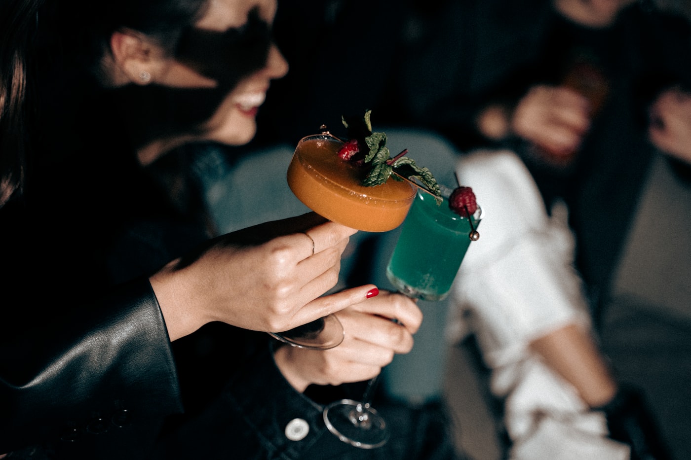 Garnished cocktail in hand with guests blurred behind