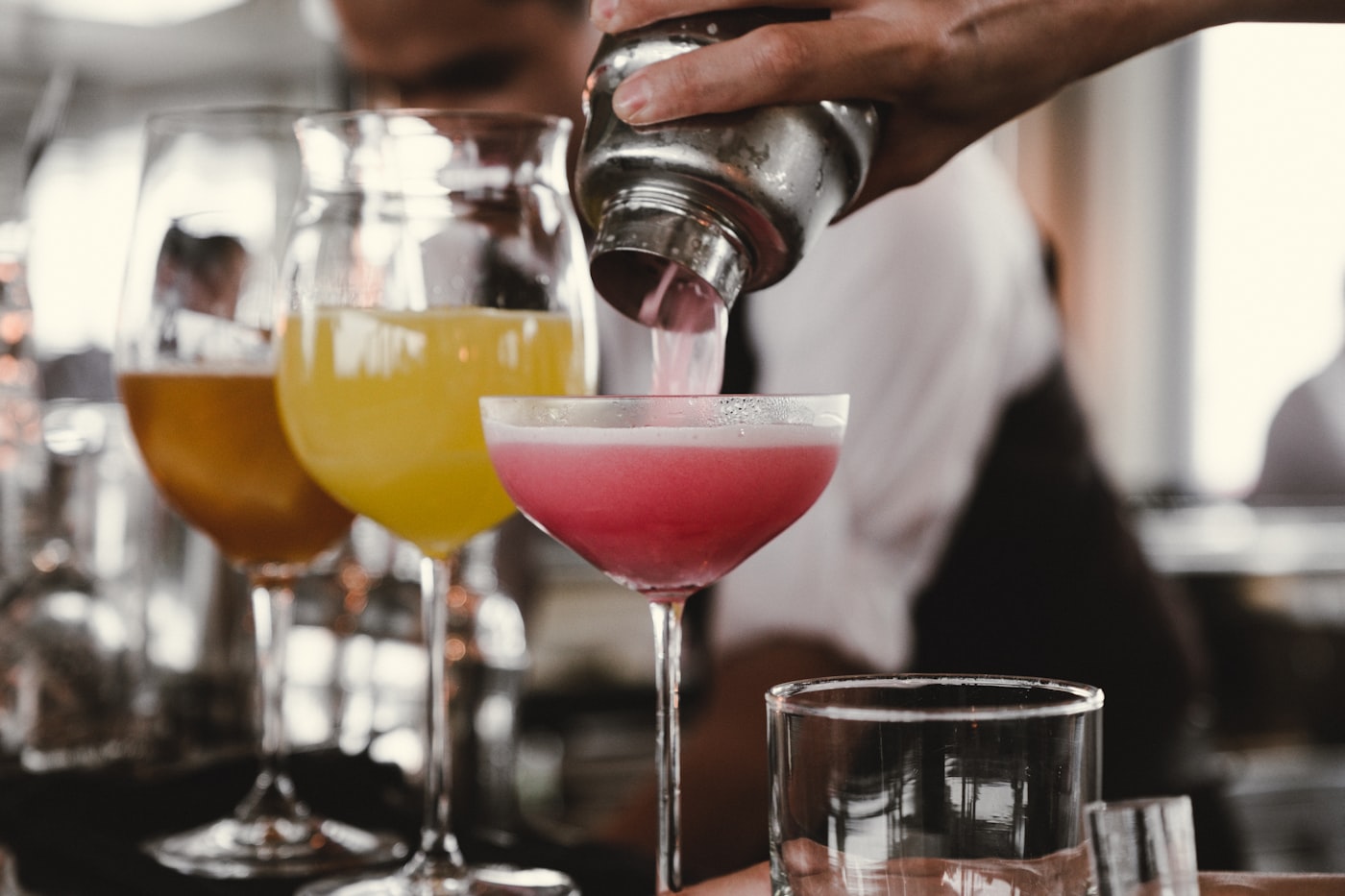 Bartender shaking a cocktail over two coupe glasses