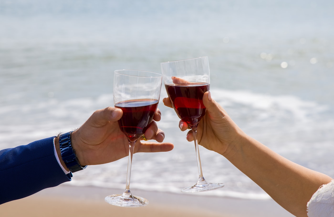 Two guests toasting glasses of wine beside the water